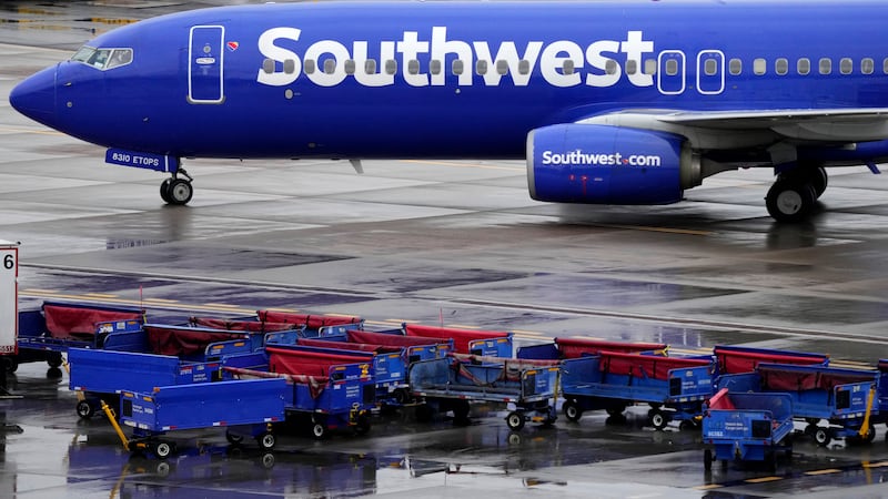 FILE - A Southwest Airlines jet passes unused luggage carts as it arrives, Dec. 28, 2022, at...