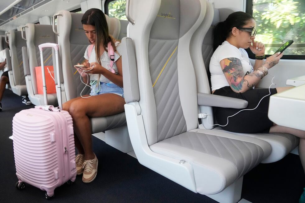 Brightline passengers look at their phones, Friday, Sept. 8, 2023, in Aventura, Fla....